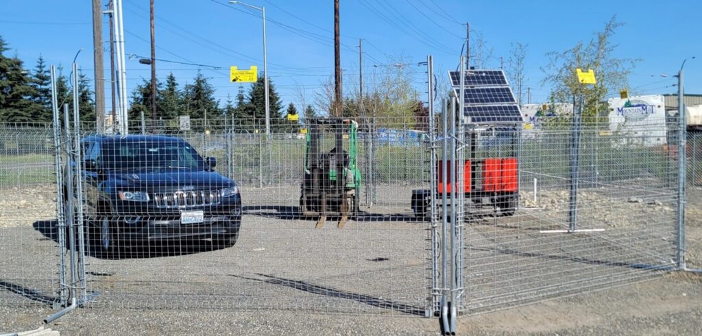 portable fencing enclosure with a car and construction equipment behind it 