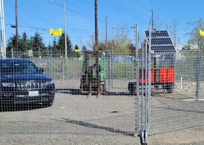 A car and construction equipment behind a portable fence to stop construction site theft
