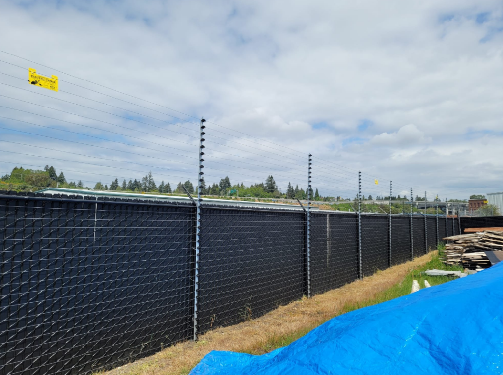 The Top 5 Essentials for a 24/7 Monitored Electric Fence black fence with electric monitoring at the top securing a lot | monitored electric fence