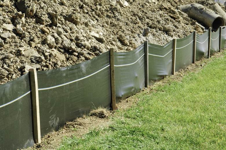 green mesh temporary fencing enclosing a mound of dirt 