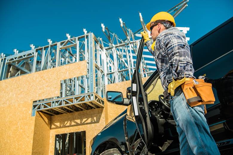 Construction worker standing outside of his truck looking at a construction site 